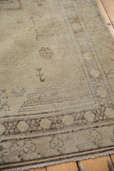 Distressed Khotan rug texture with mostly even wear, visible foundation, and faded beige and charcoal patterns.