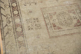 Decorative distressed vintage Khotan rug: faded beige, charcoal floral patterns, visible wear.