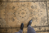 Distressed Sivas rug features black scrolling vinery on worn beige pile.