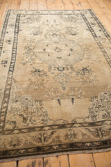 Distressed Sivas rug corner detail, with charcoal border and faded scrolling vinery on beige field.