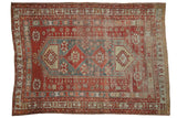 Distressed vintage Caucasian carpet, cherry red field, denim blue lozenge medallion, pinwheel motifs. 5'9