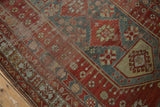 Distressed Caucasian carpet border detail: cherry red, denim blue, and saffron yellow geometric motifs.