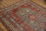 Distressed vintage rug with vibrant cherry red, blue, and saffron geometric motifs.