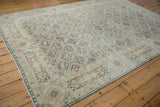Distressed Sivas carpet corner showing cartouche border, faint wear, ivory, dusty teal tones.
