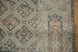 Dusty teal diamond lattice field and cartouche border of a distressed vintage Sivas rug.