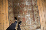 Distressed vintage Malayer rug, central floral medallion with terra cotta, beige, and pale olive.