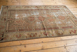 Distressed vintage Malayer rug showing a meandering palmette border and floral field in faded earth tones.