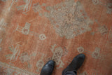 Vintage Khotan carpet's distressed burnt orange field, geometric patterns, and visible foundation.