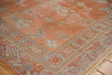 Distressed Khotan rug corner, featuring geometric floral border patterns in silver and terra cotta hues.