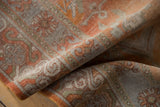 Distressed Khotan carpet pile texture, with geometric floral patterns in muted burnt orange, silver, and green.