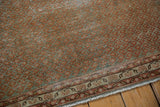 Distressed vintage Serbend rug corner with terra cotta geometric field, antique ivory border.