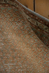 Distressed vintage Serbend rug texture showing terra cotta and oxidized silver Mir boteh pattern.