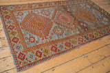 Distressed Caucasian rug's triple medallion with hook and latch motifs in blue, red, gold.