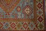 Distressed Caucasian rug detail, showing geometric patterns in slate blue, brick red, and gold.