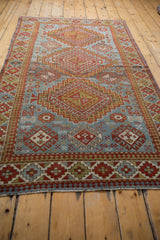 Distressed vintage Caucasian rug's bottom fringe and geometric red, blue, green border.