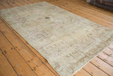 Vintage distressed Khotan rug, showing worn beige pile with charcoal outline patterns.