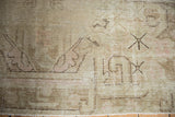 Distressed vintage Khotan rug corner, with worn pile, faint foundation, and blush plant motifs.