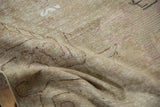 Distressed vintage Khotan rug texture, with faded beige tones and pale blush pattern details.