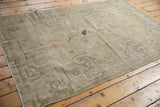 Distressed Khotan rug corner, showing worn oversize plant outlines and pale blush.