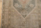 Textured view of a vintage distressed Oushak rug, showing muted beige, sand, and charcoal floral patterns.