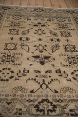 Angled view of the distressed texture and geometric starburst patterns on a vintage Persian rug.