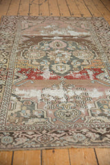 Distressed Malayer rug detail, showcasing medallion and tree of life in brick red, mauve, charcoal.