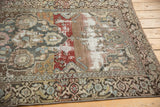 Angled view of distressed Malayer rug showing exposed foundation, brick red, and intricate border.