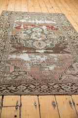 Distressed Malayer rug corner detail with exposed foundation and muted geometric border.
