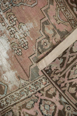 Distressed vintage Malayer rug pile showing exposed foundation, mauve, and charcoal tones.