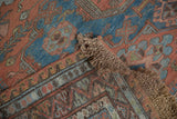 Braided fringe and geometric border of the antique distressed Soumac carpet in faded tones.