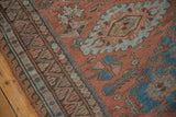 Distressed Soumac carpet close-up: madder red field, geometric zig-zag border, sky blue guls.