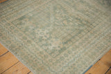 Distressed vintage Oushak rug corner with faded seafoam green and beige floral motifs.