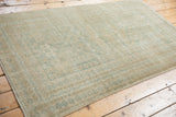 Distressed vintage Oushak rug end, showing even wear and seafoam green pattern on beige.