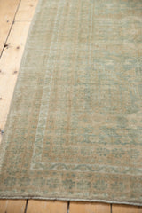Distressed pile of vintage Oushak rug showing muted seafoam green, beige tones, and even wear.