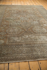 Corner of distressed Sivas carpet with geometric border, muted earth tones, and intact selvage.