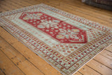 Distressed vintage Caucasian rug: cherry red field, seafoam border, pawn and floral motifs.