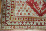 Vintage Caucasian rug corner, cherry red reciprocating pawn motif on a seafoam border.