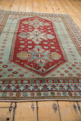 Vintage distressed Caucasian rug lower border with cherry red, seafoam, geometric and floral patterns.