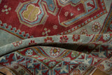 Distressed vintage Caucasian rug showing textured cherry red and seafoam geometric floral motifs.