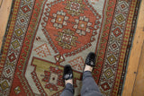 Distressed vintage Caucasian rug pile, showing even wear and geometric pawn motif in rust tones.