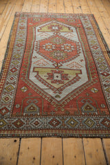 Distressed vintage Caucasian rug lower border, showing rust, gold, and silver geometric patterns.