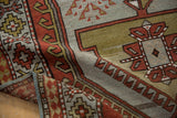 Distressed Caucasian rug texture with geometric rust and dusty gold motifs.