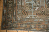 Distressed Belouch rug corner showing geometric patterns, faded tones, and visible fringe.