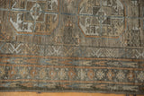 Distressed Belouch rug close-up showing textured pile, geometric guls, and subtle chestnut, silver tones.