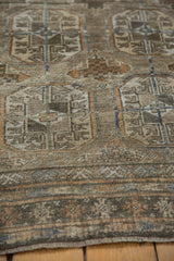 Visible fringe and striped border of the distressed Belouch rug, with time-softened copper and silver tones.