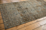 Distressed vintage Belouch rug end with worn pile, geometric motifs in muted silver and copper.
