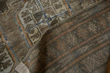 Folded vintage Distressed Belouch runner showing muted geometric gul motifs and exposed foundation.