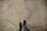 Faded ivory and beige tones on distressed Sivas carpet with Herati field and agricultural border.