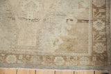 Distressed Oushak rug corner with subtle beige patterns, even wear, and short fringe.