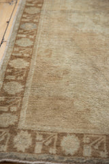 Close-up of distressed Oushak rug showing muted beige pile, even wear, and brown border.